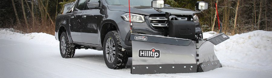 Pickup med frontmontert brøyteplog rydder snø på en vinterlig vei