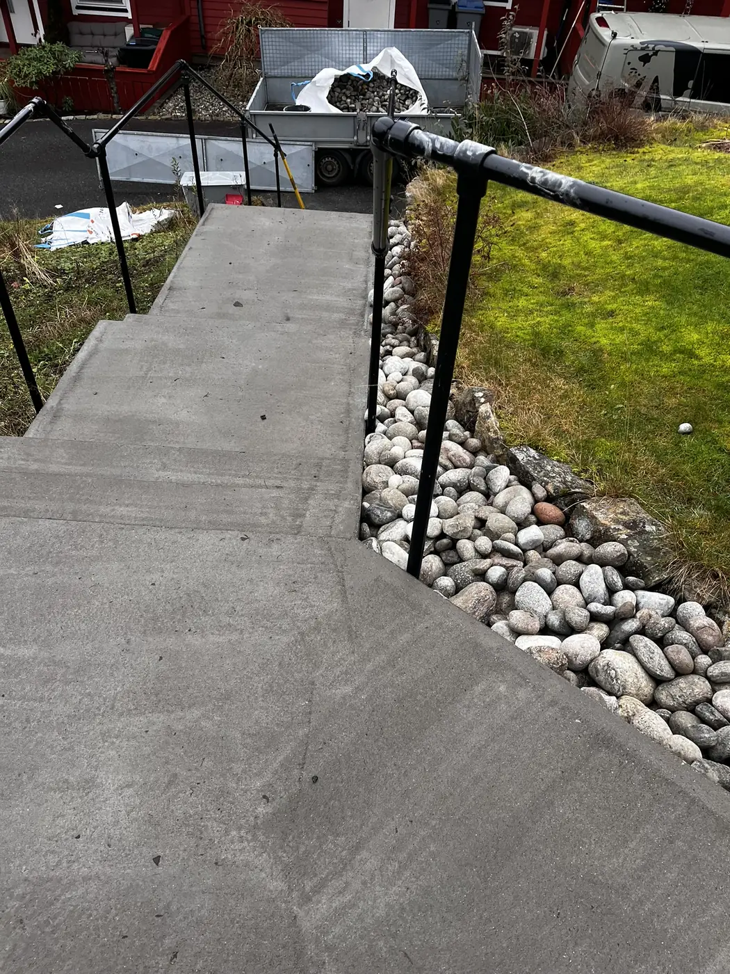 Betongtrapp med rekkverk og rundstein langs kanten